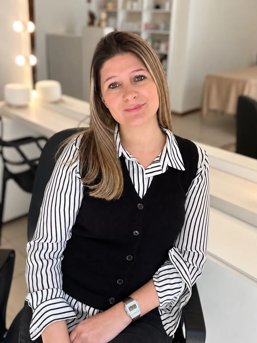 Agustina Núñez sentada en AN Estética Integral, su centro en Pilar, con el espejo de maquillaje y las estanterías de producto detrás.